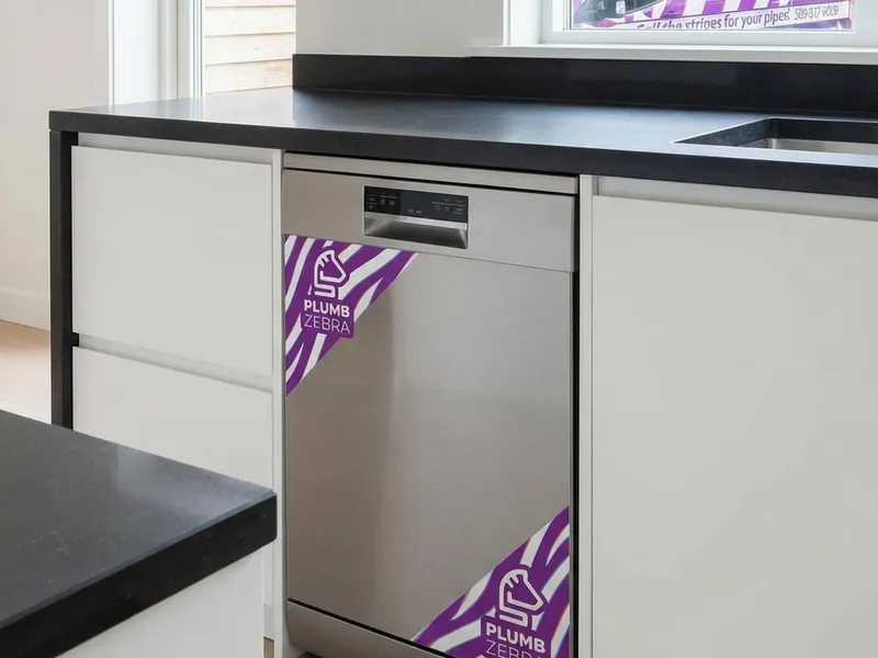 Professional plumber installing dishwasher with proper water and electrical connections
